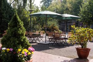 un patio con tavoli, sedie, ombrelloni e fiori di ibis Berlin City Nord a Berlino