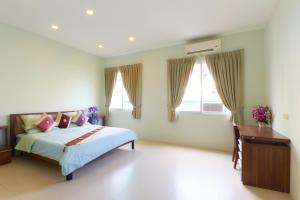 a bedroom with a bed and a desk and windows at Season Residence in Phnom Penh