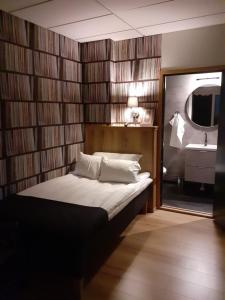 1 dormitorio con cama con espejo y lavamanos en Hotell Greven en Vårgårda