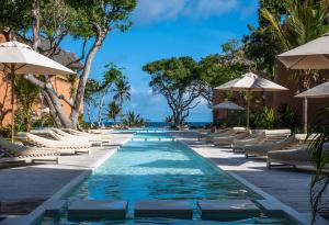 una piscina en el complejo con tumbonas y sombrillas en Medina Palms en Watamu