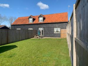 a backyard with a wooden fence and a house at Hideaway Cottage in Halesworth