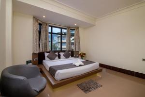 a bedroom with a bed and a chair at Muscatel Yavachi - 400 Mts from MG Marg in Gangtok