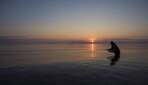 a man standing in the water with a fishing rod at Egn Boutique Hotel in Stege
