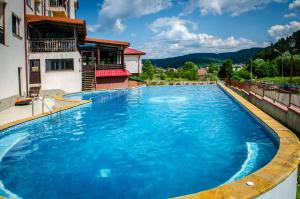 a swimming pool with blue water in front of a building at апартаменти Tryavna lake in Tryavna