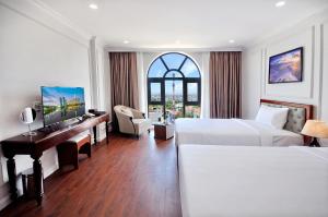 a hotel room with two beds and a desk at Sunflower Hotel Phú Yên in Tuy Hoa