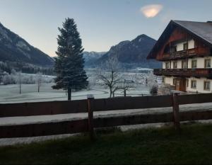 ein Zaun vor einem Haus und einem Baum in der Unterkunft Leiterhof inkl. Chiemgaukarte in Ruhpolding