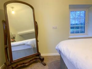 a bedroom with a mirror next to a bed at Ballyharvey Gate Lodge in Muckamore