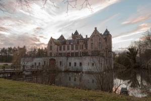 un viejo castillo sentado sobre un cuerpo de agua en Casa Tilleghem, en Brujas