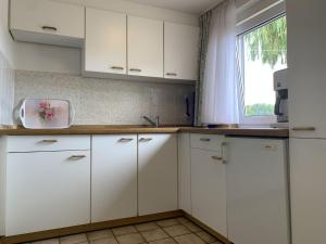 達默的住宿－Haus Sonnenwinkel - Bungalow 5，厨房配有白色橱柜和窗户。
