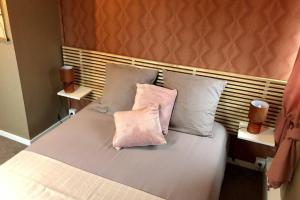 uma cama com duas almofadas cor-de-rosa em cima em Gite PIPIOU ETAPLES 2 à 4 Personnes em Étaples