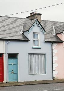 a white house with a blue door and a red garage at The Small House in Listowel