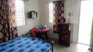 Una habitación con una cama y una mesa en una habitación en Vamoose Murti Homestay, en Chālsa Mahābāri