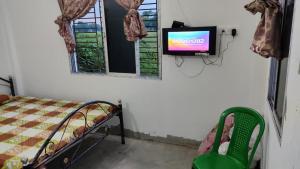 Habitación con cama y TV en la pared. en Vamoose Murti Homestay, en Chālsa Mahābāri