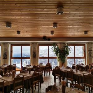 un comedor con mesas, sillas y ventanas en Albergo Ristorante Sargas, en Cevo