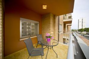 a balcony with a table and chairs and a vase of flowers at Bali Orangecosta in Benicàssim