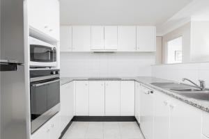Una cocina blanca con fregadero y microondas. en BreakFree Capital Tower Apartments, en Canberra