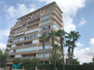 ein hohes Gebäude mit Palmen davor in der Unterkunft Oasis 1A Playa Arenal Calpe in Calpe