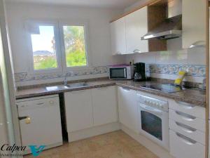 eine weiße Küche mit einer Spüle und einer Mikrowelle in der Unterkunft Oasis 1A Playa Arenal Calpe in Calpe