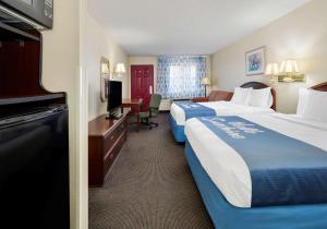 Days Inn & Suites by Wyndham Bentonville في بنتونفيل: غرفة فندقية بسريرين وتلفزيون بشاشة مسطحة
