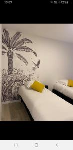a bedroom with two beds with a mural of a palm tree at Belle vue D'Olhain in Fresnicourt-le-Dolmen