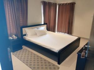 1 cama con sábanas blancas y almohadas en una habitación en Maui Resort, en Cox's Bazar