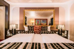 ein Schlafzimmer mit einem großen Bett und einem Spiegel in der Unterkunft Golf & Alpin Wellness Resort Hotel Ludwig Royal in Oberstaufen
