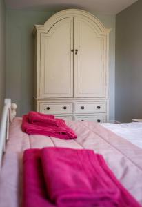 a bedroom with a bed with pink sheets and a dresser at Stable Cottage - Milton Lilbourne in Pewsey