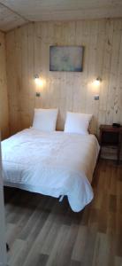 1 dormitorio con cama blanca y pared de madera en chalets les 5 loups, en Gerbépal