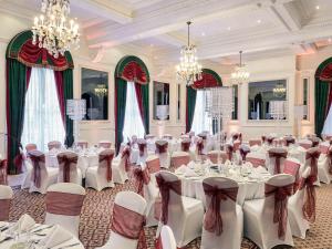a banquet hall with white tables and chairs and chandeliers at Mercure Bristol Grand Hotel in Bristol