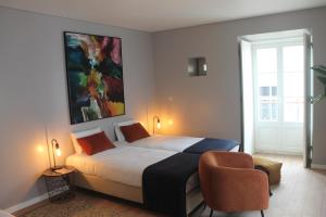 a bedroom with a large bed and a chair at CASA DAS QUATRO CABEÇAS in Setúbal