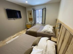 ein Hotelzimmer mit 2 Betten und einem Flachbild-TV in der Unterkunft L'Arche de Porquerolles in Porquerolles