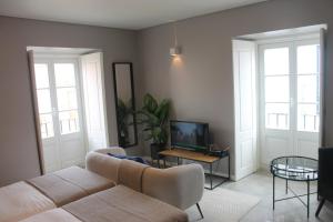 a living room with a couch and a tv at CASA DAS QUATRO CABEÇAS in Setúbal