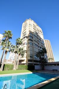 un gran edificio de apartamentos con piscina y palmeras en Apartamentos Mariscal VII, en Benidorm