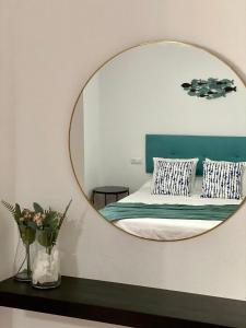 a mirror on a wall above a bed with pillows at Apartamentos Turísticos Carmencita in Bolonia