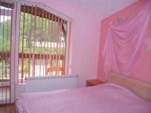 een slaapkamer met een roze bed en een raam bij Sveti Georgi Family Hotel in Varshets
