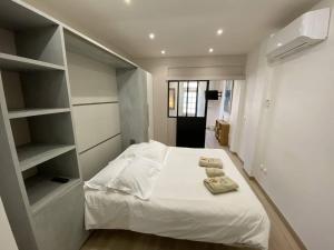 a bedroom with a bed with white sheets and shelves at L'Arche de Porquerolles in Porquerolles
