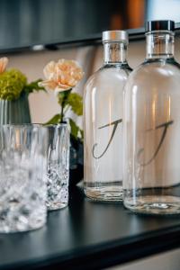 drie flessen en glazen op een tafel met bloemen bij Jaumann's Südwind Sylt in Westerland