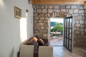 a living room with a couch and a stone wall at Sweet Old Stone House Cavtat in Cavtat