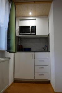 a kitchen with white cabinets and a microwave at FerienZimmer in Niederstetten