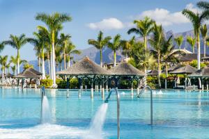 - une piscine dans un complexe avec des palmiers dans l'établissement Gran Melia Palacio de Isora Resort & Spa, à Alcalá