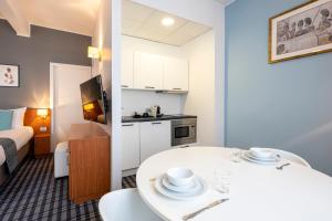 a small apartment with a white table and a kitchen at Leopold Hotel Ostend in Ostend