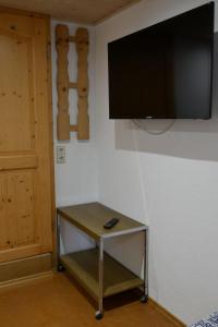 a television hanging on a wall with a table with a remote at FerienZimmer in Niederstetten