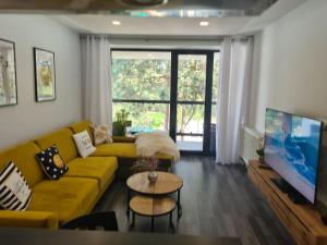 a living room with a yellow couch and a tv at 365 apartmány LINEA in Piešťany