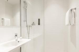 a white bathroom with a shower and a sink at B&B HOTEL Basel in Basel