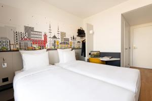 a large white bed in a room with a wall at B&B HOTEL Basel in Basel