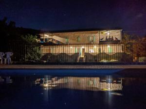 un edificio con un reflejo en el agua por la noche en La Maison du Chassezac en Les Assions