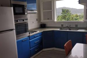 a kitchen with blue cabinets and a sink and a window at Loue maison en Martinique in Le Vauclin