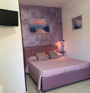 ein Schlafzimmer mit einem lila Bett mit einer Wand in der Unterkunft Monolocale Viola - A casa di Ludovica e Martina in Gallipoli
