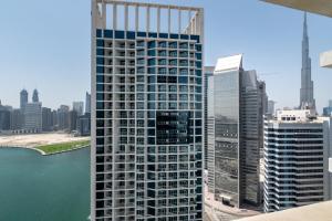 a tall building next to a body of water at The Smart Concierge - Damac Maison Prive in Dubai