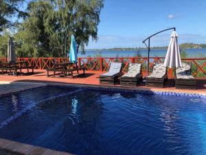 a swimming pool with chairs and umbrellas next to at Villa Espanhola Bilene in Vila Praia Do Bilene